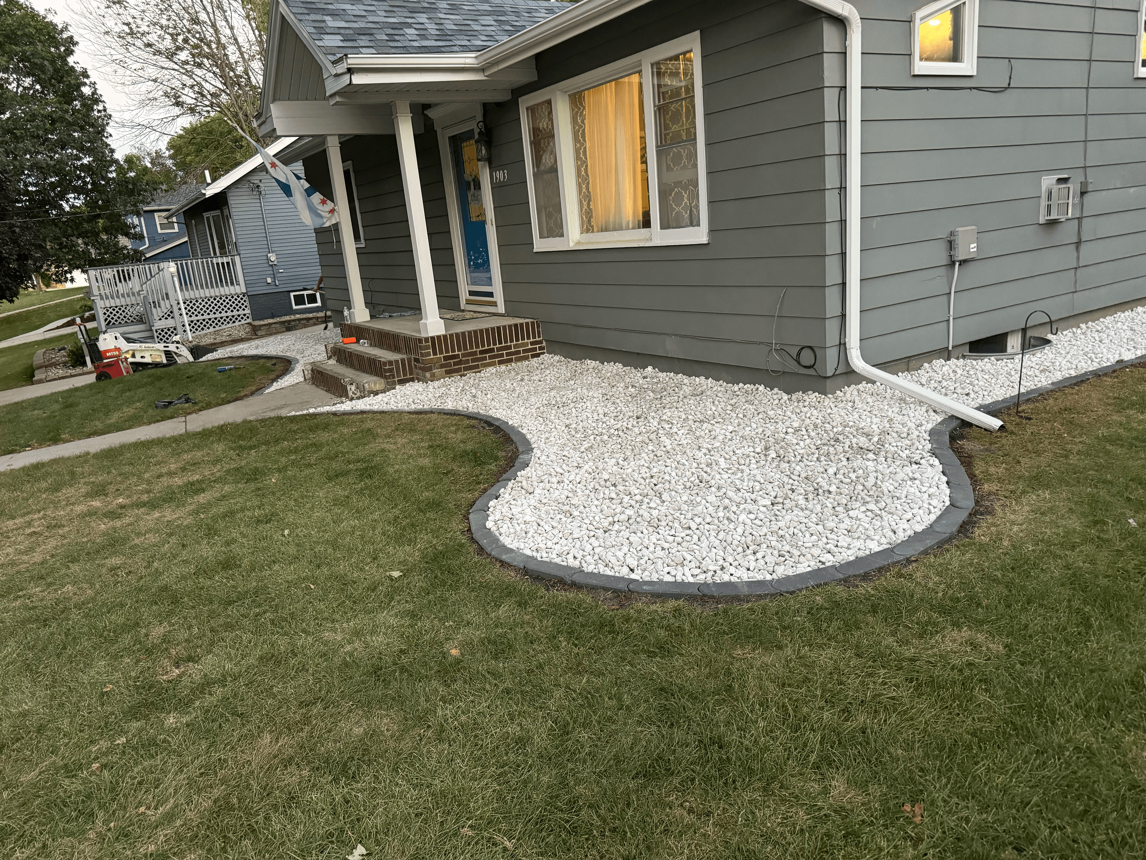 Grey house with a curved white stone landscape bed and dark grey stone border.